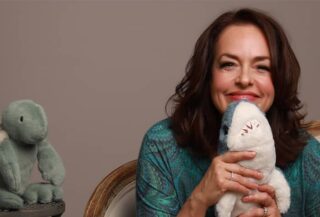 photo of Dr Mona Delahooke smiling holding a stuffed shark toy